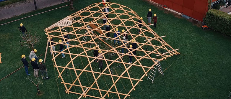 Menschen arbeiten an einem Holzkonstrukt in Wabenform