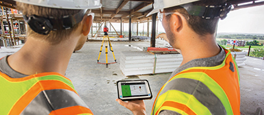 Zwei Bauarbeiter analysieren Messungen auf der Baustelle