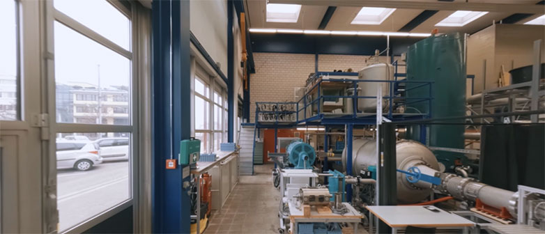 Engineering laboratory with industrial equipment, piping systems, and large machines.