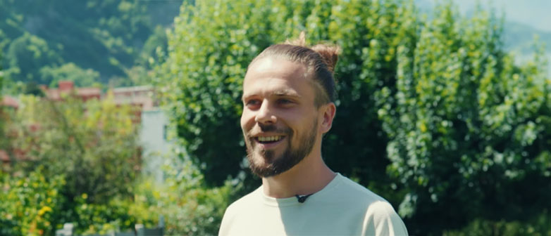 Person wird interviewt im Freien vor grüner Landschaft.