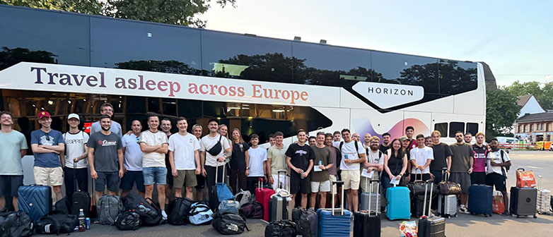 Reisegruppe mit Gepäck vor einem Reisebus mit der Aufschrift „Travel asleep across Europe“.