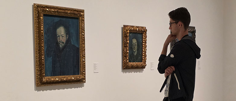 Besucher betrachtet gerahmte Porträts in einer Kunstausstellung.