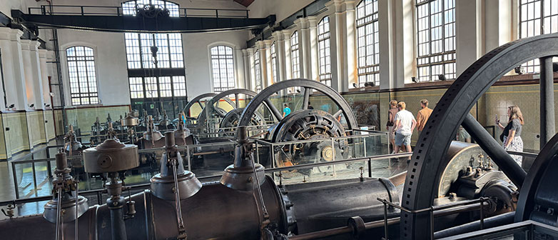 Historische Industrieanlage mit großen Schwungrädern und Maschinen in einer weitläufigen Ausstellungshalle.