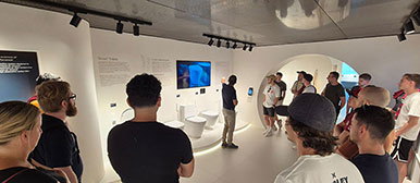 Gruppe bei einer Führung durch eine moderne Ausstellung zu Sanitärtechnik und Toiletten.