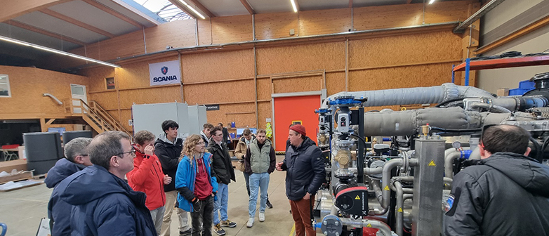 Philipp Heining (in roter Kappe) erklärt die Funktionsweise der firmeneigenen Blockheizkraftwerke.