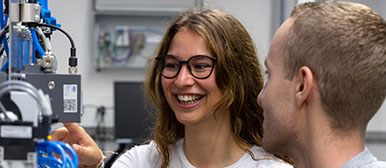 Eine Studentin und ein Student begutachten sich ein technisches Gerät