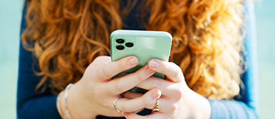 Eine rothaarige Frau hält ein Smartphone 