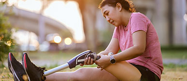Frau am Boden sitzend mit Beinprothese