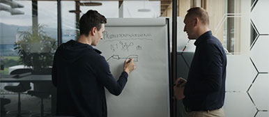 Andi Tonazzi steht mit jemandem vor einem Whiteboard