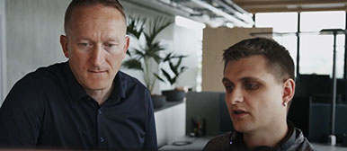 Zwei Männer besprechen etwas vor einem Monitor.