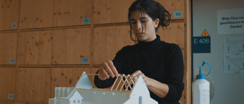 Eine junge Frau arbeitet an einem Modell eines Gebäudes