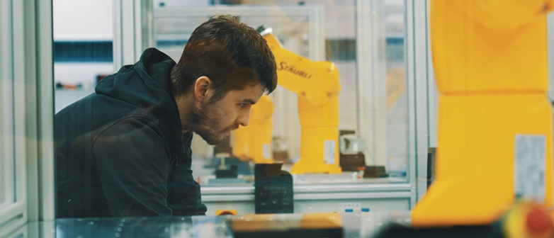 Ein junger Maschinenbauingenieur arbeitet mit Roboterarmen