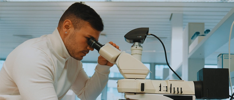 Ein junger Medizintechniker schaut durch ein Mikroskop