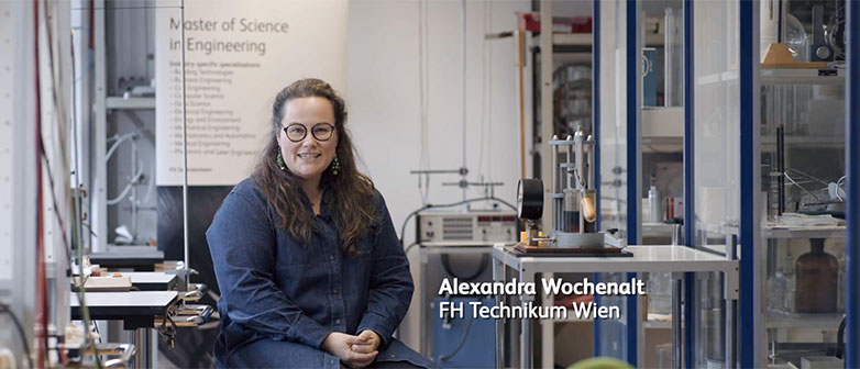 Person sitting in a technical laboratory surrounded by equipment and experimental setups.
