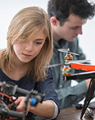 Zwei Studierende arbeiten an kleinen Flugdrohnen