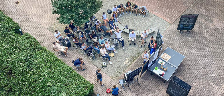 Gruppe von Studierenden geniesst den Unterricht draussen auf dem Campus.