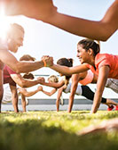 Gruppe von Menschen bei einhändigen Liegestützen