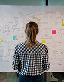 Studierende vor einer Wand voller beschriebener Flipcharts