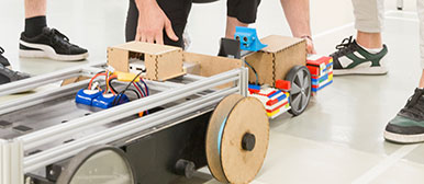 Ein Kleine Gruppe Studierender steht um den Prototyp ihres elektrisch unterstützenden Fahrradanhängers.