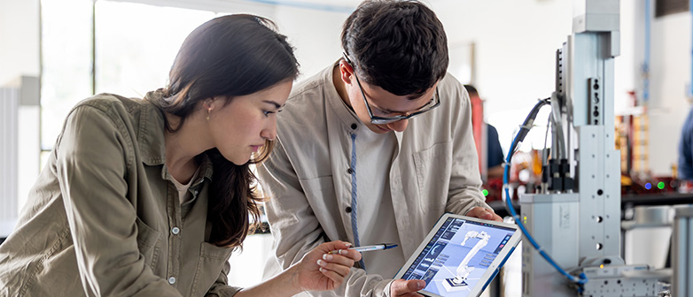 Eine junge Frau und ein junger Mann besprechen einen Plan eines Roboterarms auf einem Tablet