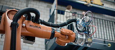 Ein oranger Roboterarm streckt sich nach Rechts