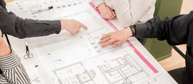 Hände zeigen auf einen architektonischen Plan