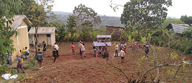 Studierende montieren Solar-Panelen in einem Dorf und die einheimischen Kinder schauen zu