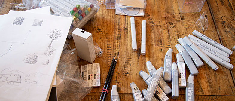 Foto zeigt einen Tisch, auf dem viele Stifte und Papiere liegen. Kreatives Chaos.