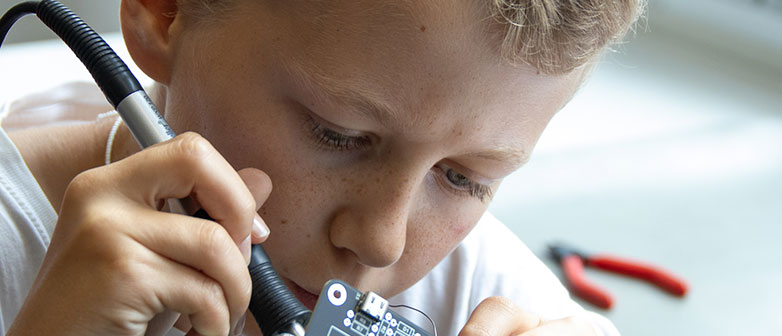 Ein Junge arbeitet konzentriert mit einem Lötkolben