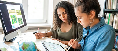 Zwei junge Frauen arbeiten zusammen am Computer