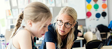 Eine Frau erklärt einem Mädchen etwas in einem Klassenzimmer
