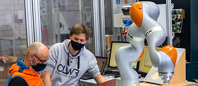 Automatisierungstechnik: 2 Männer schauen auf einen Bildschirm neben einem Roboter