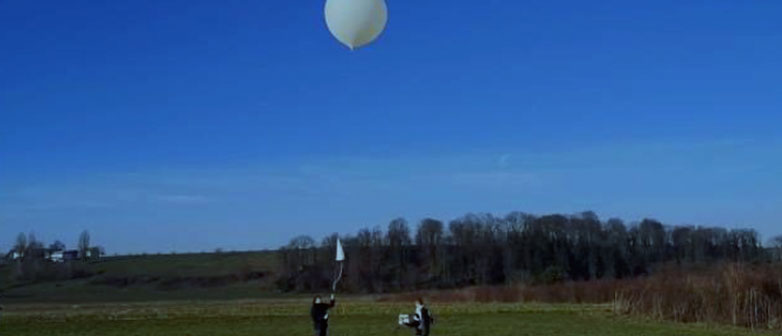 Zwei Studierende mit Wetterballon auf Wiese