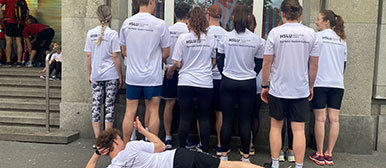 Eine Gruppe Studierender steht mit dem Rücken zur Kamera, der Fokus liegt auf dem T-Shirt mit der Aufschrift 