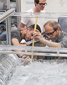 Drei Personen untersuchen zerbrochenes Glas bei einem Versuch im Labor
