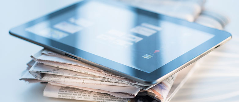 Tablet on a stack of newspapers