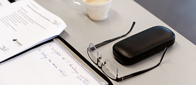 Schreibblock mit Notizen, Brille und Kaffee auf Schreibtisch