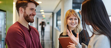 Drei Studierende sprechen im Flur des Departements miteinander