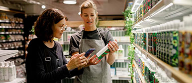 Verkäuferin und Kundin stehen an einem Getränkeregal