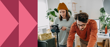 Zwei Personen arbeiten kreativ in einem modernen Büro – eine bedient eine Kamera, die andere arbeitet konzentriert am Laptop. Symbolbild für praxisorientiertes Storytelling und visuelle Markenkommunikation.