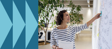 Eine Fachperson platziert ein Post-it auf einer Wand voller Skizzen und hält dabei Unterlagen – Symbolbild für datenbasierte Entscheidungsprozesse, visuelle Planung und strategische Analyse im Arbeitsalltag.