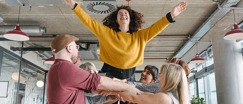 Frau wird von anderen Menschen in die Luft geworfen
