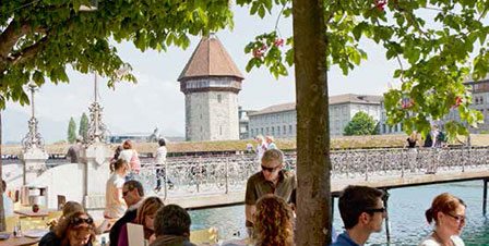 Restaurant mit Gästen in Luzern, im Hintergrund der Wasserturm und die Kappelbrücke