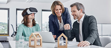 Zwei Frauen und ein Mann am Tisch mit Häusern aus Holz