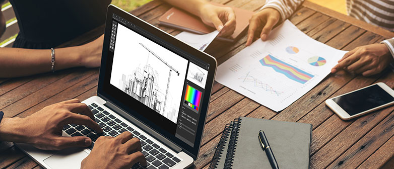 Drei paar Hände mit Laptop und Papier am Tisch