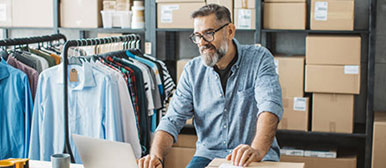 Mann vor Kleiderständern und Kartons