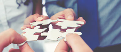 Vier Hände, die Puzzleteile zusammenstecken