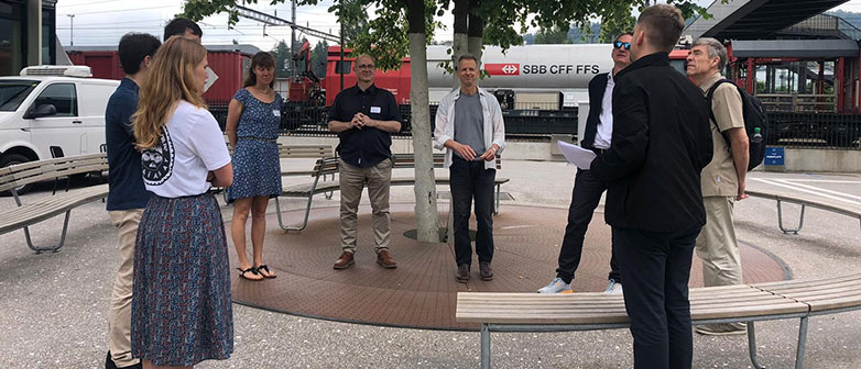 Personen stehen im Kreis am Bahnhof Rotkreuz vor der Suurstoffi