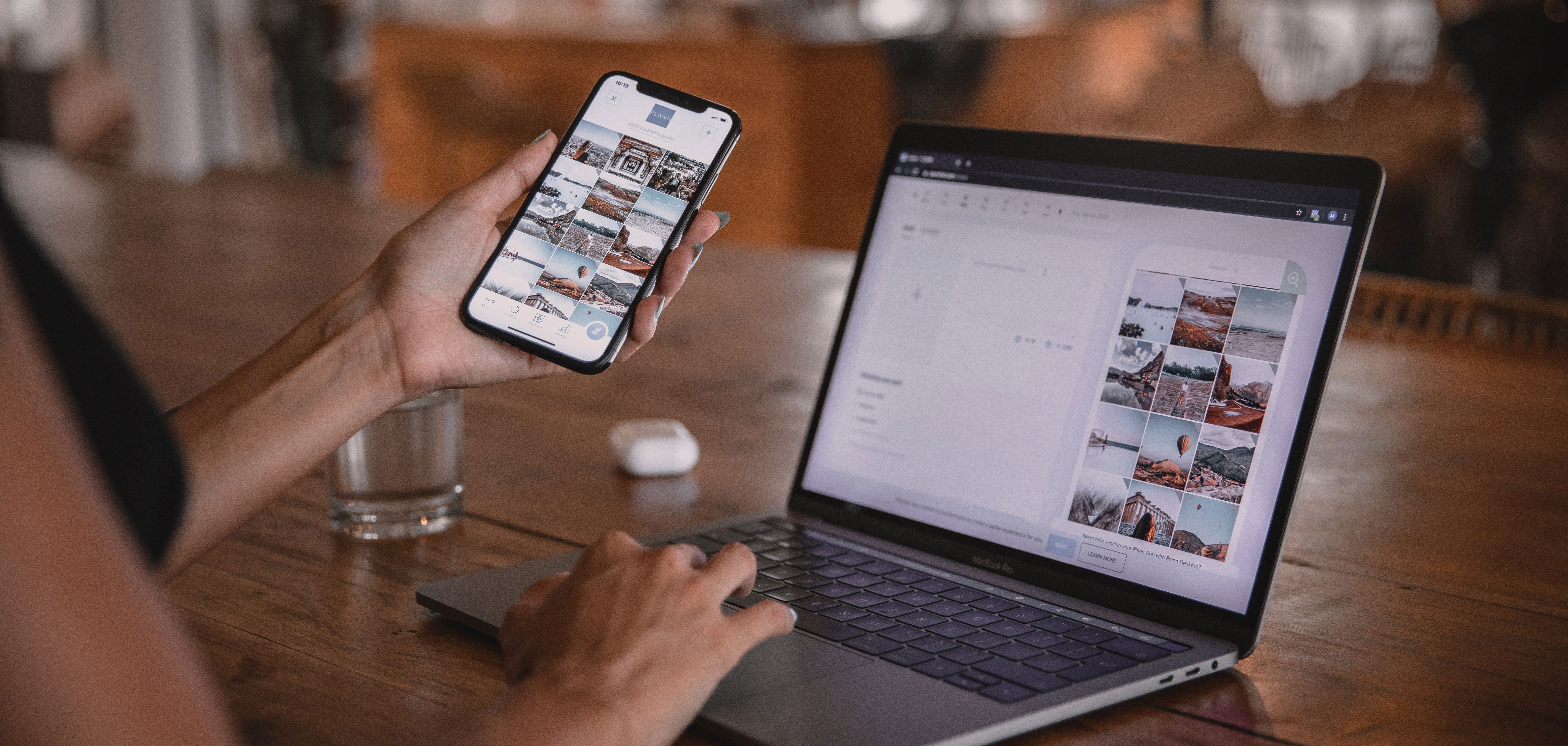 Frau hält Handy in der Hand und arbeitet am Laptop