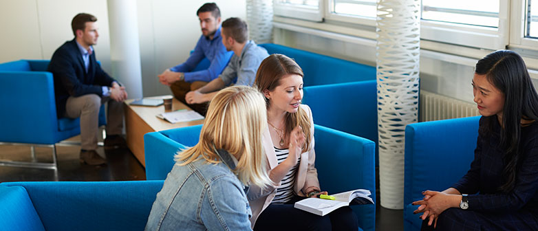 Studierende besprechen sitzend auf Sofas